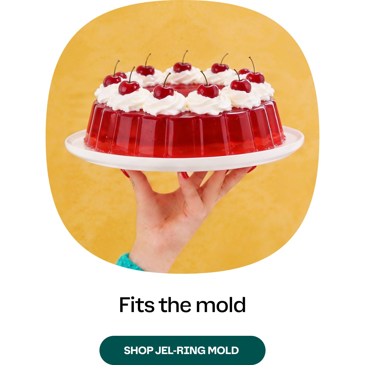 Red jell mold with whipped cream and cherries on a yellow background. Shop Jel-Ring mold.